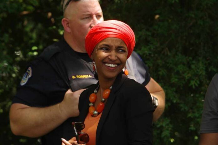Smiling woman in a red headscarf at a community event with a police officer in the background