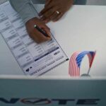 A person filling out a ballot in a voting booth