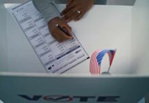 A person filling out a ballot in a voting booth