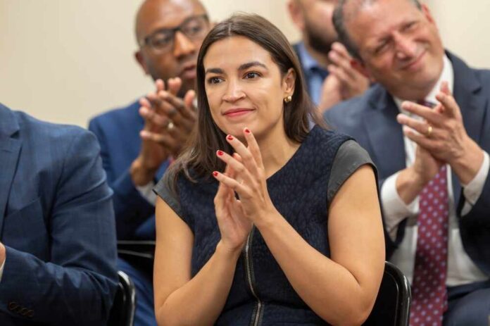 shutterstock_2467431681.jpg A woman in a dark dress clapping at a political event with an engaged audience in the background