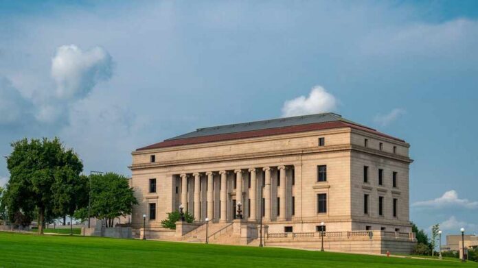 shutterstock_2504474747.jpg A historic building with columns and a red roof set against a cloudy sky