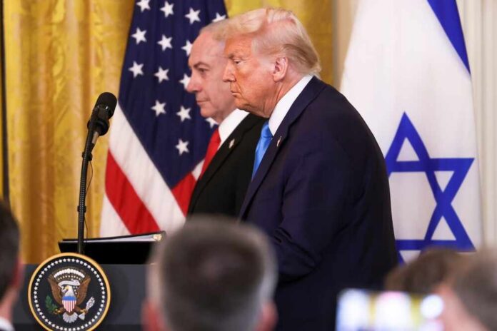 Donald Trump and another official at a press conference with flags in the background