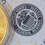 Close-up of a gold coin next to a US dollar bill