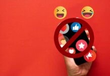 A hand holding a smartphone with social media icons and a prohibition sign