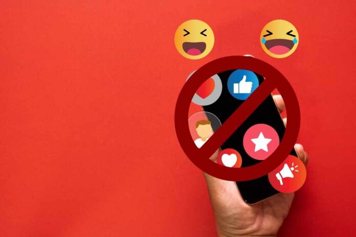 A hand holding a smartphone with social media icons and a prohibition sign