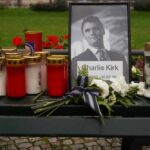Memorial setup with candles, flowers, and a framed photograph