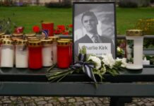 Memorial setup with candles, flowers, and a framed photograph