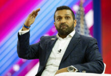 A man in a suit gesturing while speaking at a conference