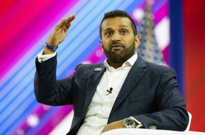 A man in a suit gesturing while speaking at a conference