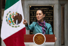 Geopolitical Tensions Hit World Cup Stage A government official delivering a speech in front of the Mexican flag