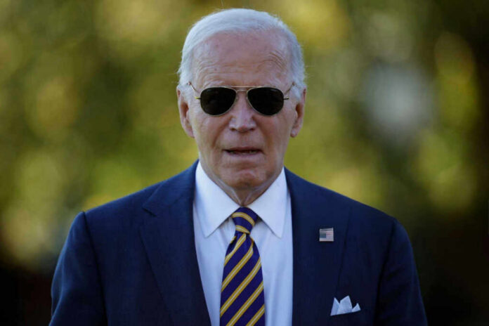 Man wearing sunglasses and a suit with an American flag pin