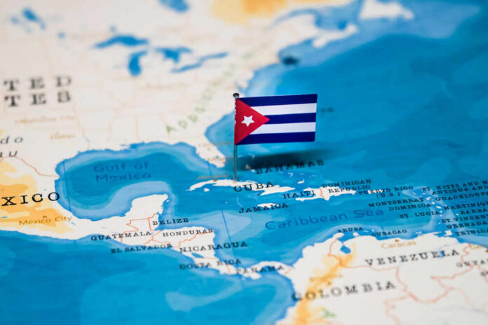 The,Flag,Of,Cuba,In,The,World,Map A small Cuban flag placed on a map highlighting Cuba in the Caribbean
