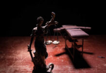 Statue of Lady Justice holding scales in a dimly lit setting