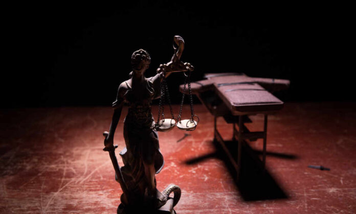 Statue of Lady Justice holding scales in a dimly lit setting