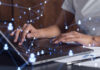 Person typing on a laptop with digital connection graphics overlay