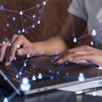 Person typing on a laptop with digital connection graphics overlay