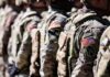 TRUMP “MIGHT” Move Troops—NATO Panics Line of soldiers in military uniforms with American flag patches