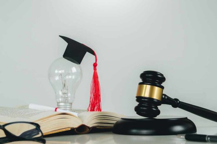 Light bulb with graduation cap beside open law book and judge’s gavel