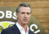 A man in a suit speaking at an outdoor event with a microphone
