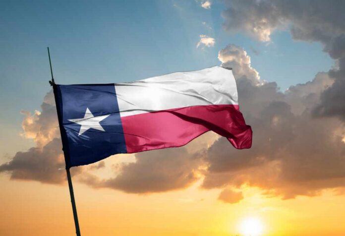 Texas flag waving against a sunset backdrop with clouds