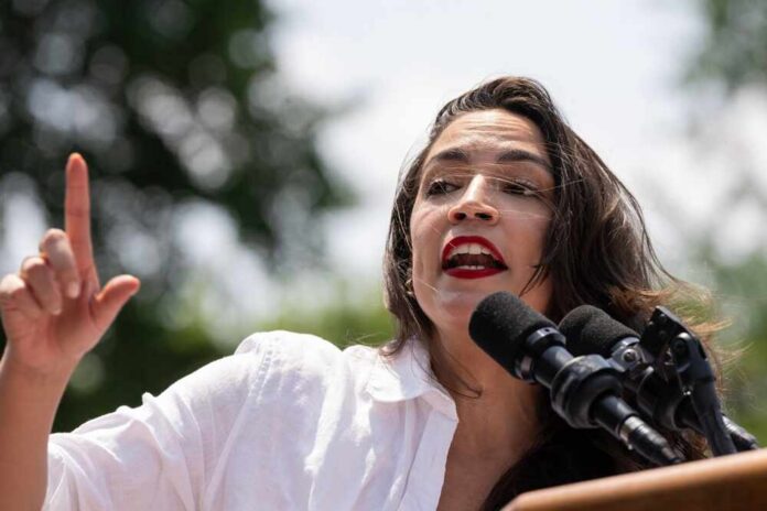 A woman passionately speaking at a rally with microphones in front of her