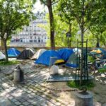 Tents set up in a city park surrounded by trees