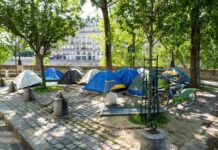 Tents set up in a city park surrounded by trees