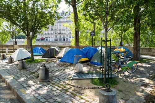 Tents set up in a city park surrounded by trees