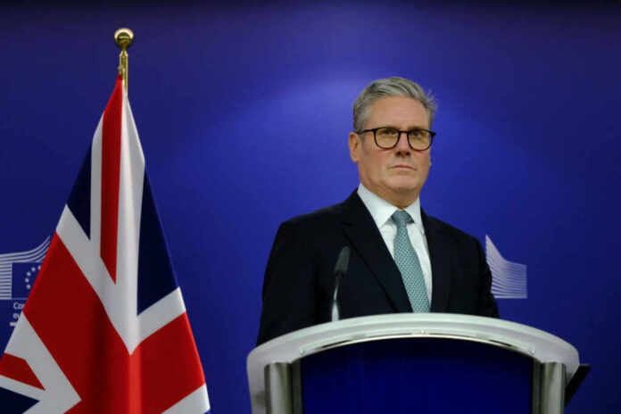shutterstock_2524974423 A political leader standing at a podium with a British flag in the background