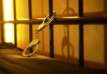 Facebook Meme Lands Retired Officer in Jail! Close-up of handcuffs attached to a bed frame