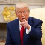 Shocking Media Clash: ‘Seditious’ Narratives Exposed A man in a blue suit and red tie pointing while seated