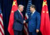Two political leaders shaking hands in front of national flags