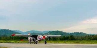 Small propeller plane on rural runway with hills in the background