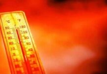 A thermometer held against a sunset city skyline