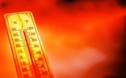 A thermometer held against a sunset city skyline