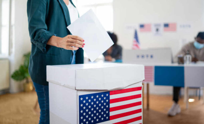 shutterstock1823718650jpg A person casting a vote into a ballot box at a polling station