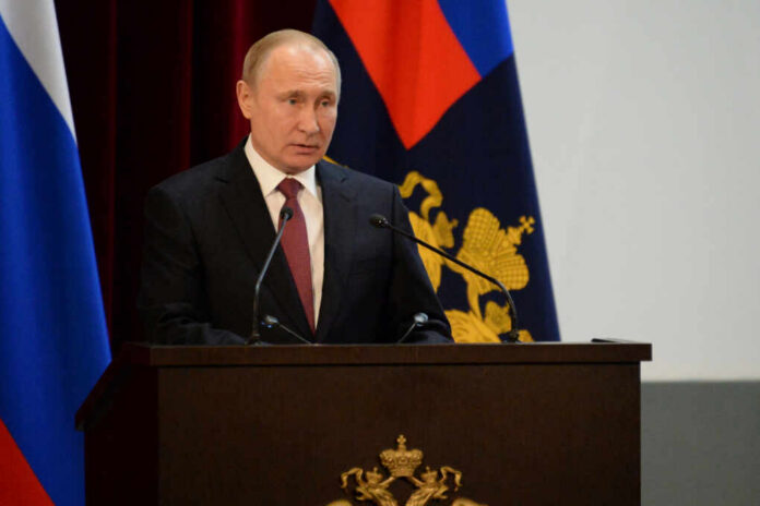 A government official delivering a speech at a podium with national flags in the background
