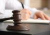 Free Speech Showdown: ICE Gets Overruled A gavel on a desk with a blurred hand writing in the background