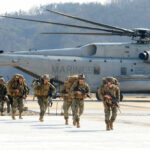 America’s Hidden Weapons Depot Down Under Marines in combat gear walking towards a helicopter