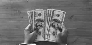 Hands in handcuffs holding stacks of cash