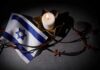 Ceasefire Theater Exposed — Rockets Still Fly Israeli flag next to a lit candle and barbed wire