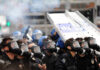 Encrypted J6 Cache Suddenly Resurfaces Riot police in gas masks with shields amid smoke