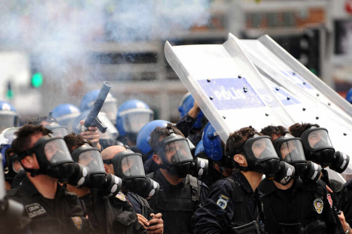 Riot police in gas masks with shields amid smoke