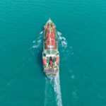 Aerial view of a cargo ship navigating through turquoise waters