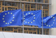 Europe’s Migration Pact Takes Effect Three European Union flags waving in front of a building
