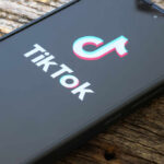A TikTok Trend Sent Kids To Burn Units Close-up of a smartphone displaying the TikTok logo on a wooden surface