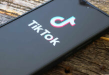 Close-up of a smartphone displaying the TikTok logo on a wooden surface