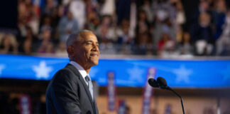 A speaker at a podium addressing an audience during a political event