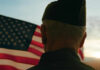 Trump Honors Veterans For Extraordinary Valor A veteran in uniform standing in front of an American flag during sunset