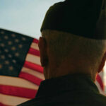 Trump Honors Veterans For Extraordinary Valor A veteran in uniform standing in front of an American flag during sunset